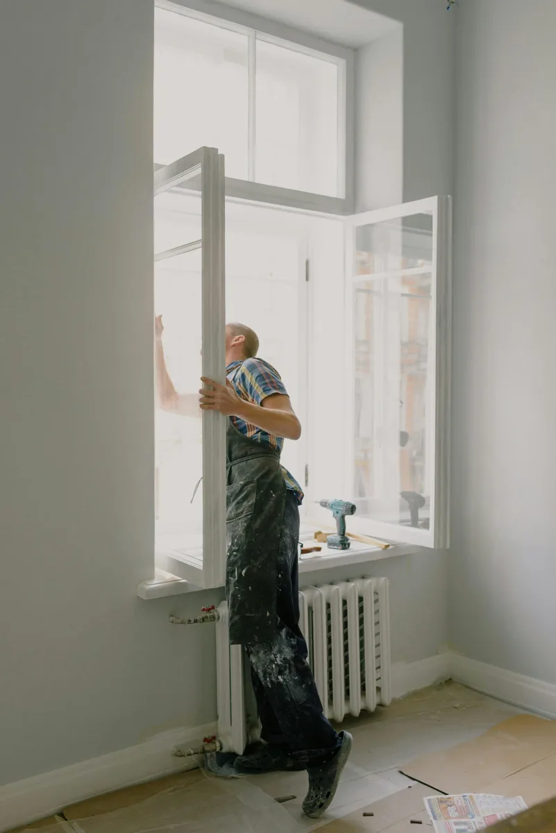 Persona reformando el marco de una ventana en una vivienda en obras