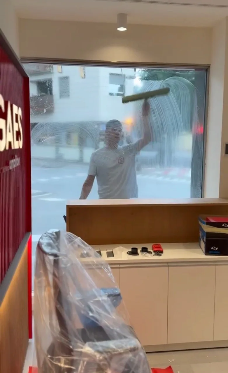 Empleado de Servicios24 limpiando el cristal del escaparate de la nueva tienda GAES en Barcelona