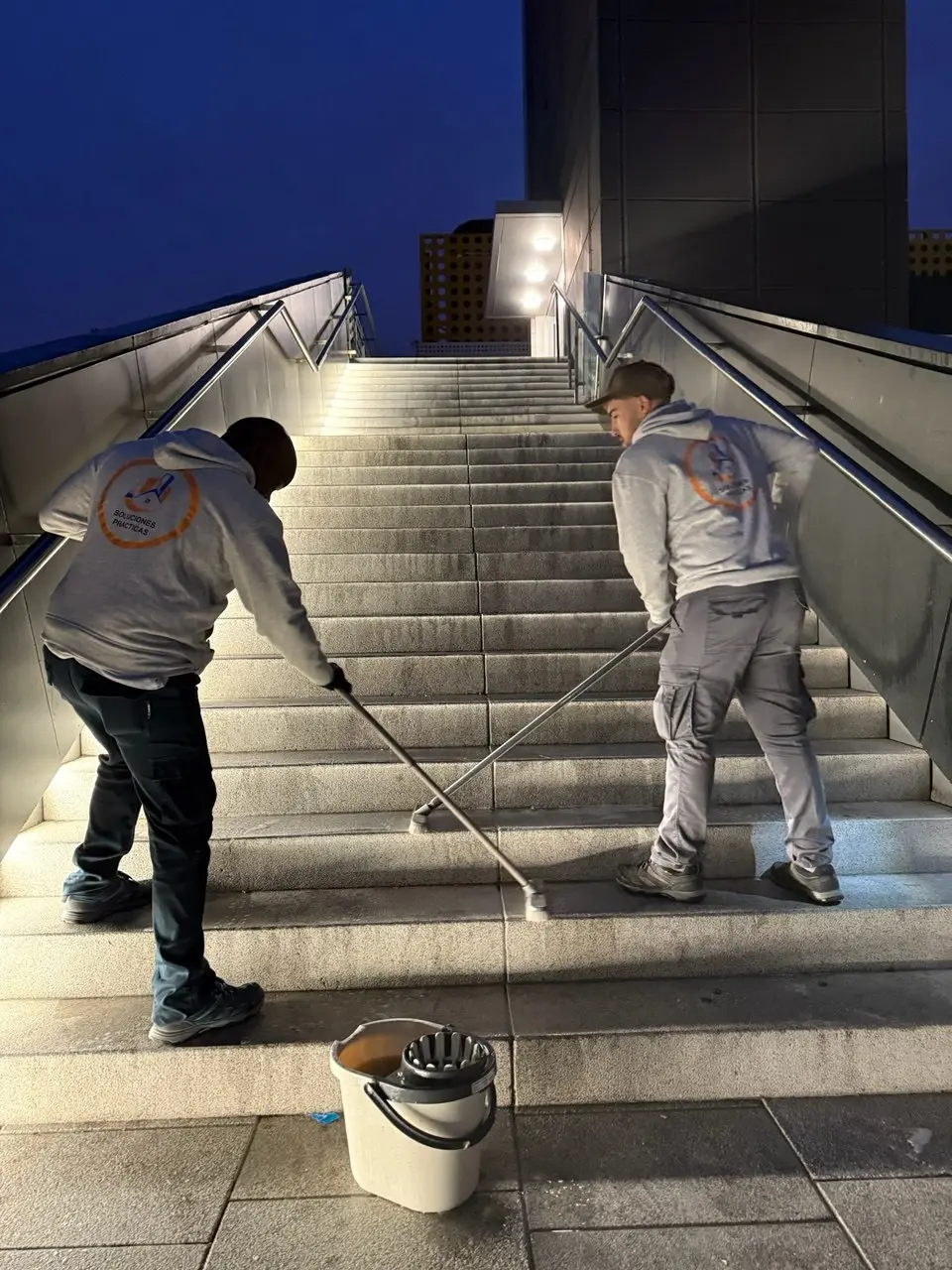 Empleados de Servicios24 limpiando unas escaleras exteriores de The Style Outlets Madrid de noche